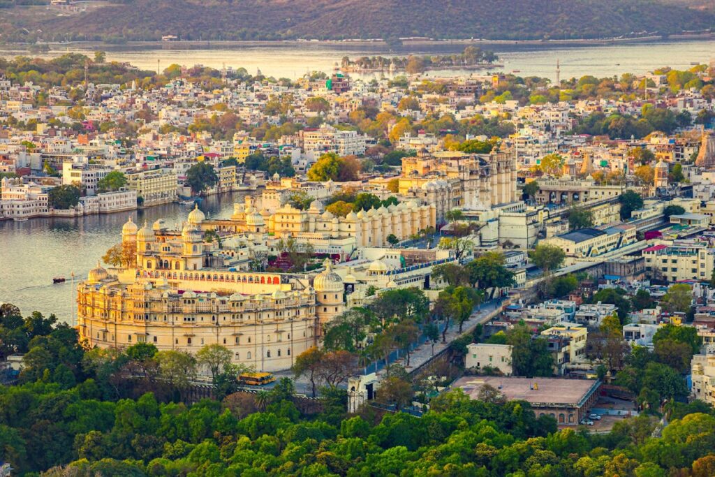 A stunning aerial view of Udaipur's City Palace overlooking Lake Pichola, showcasing its Mughal architecture.