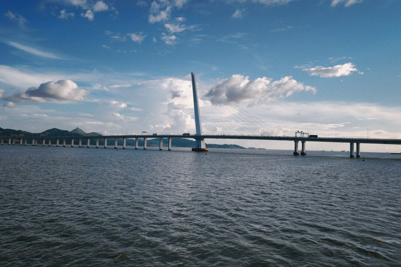 portfolio-08 Panoramic view of a cable-stayed bridge in China crossing a vast body of water under a bright blue sky.